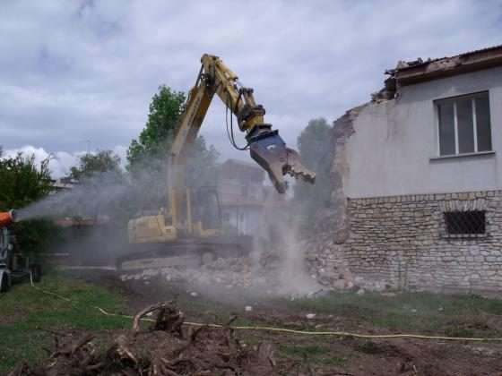 Escavatore con pinza demolitrice durante una demolizione